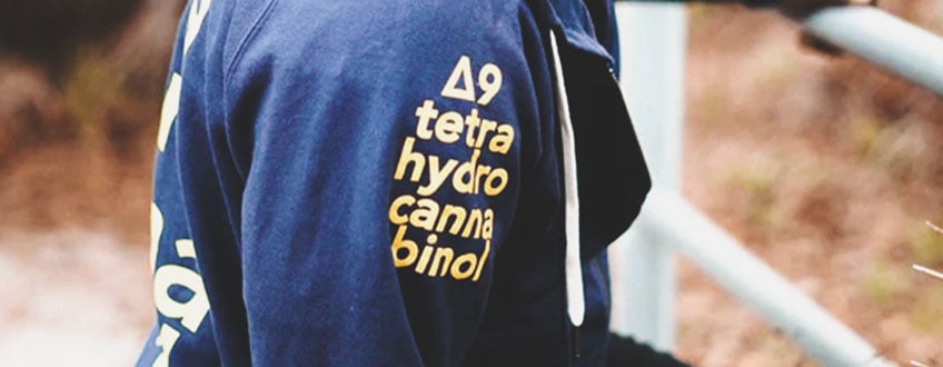 THC Hoodie Een blauwe hoodie met de chemische formule voor THC op de mouw gedrukt.