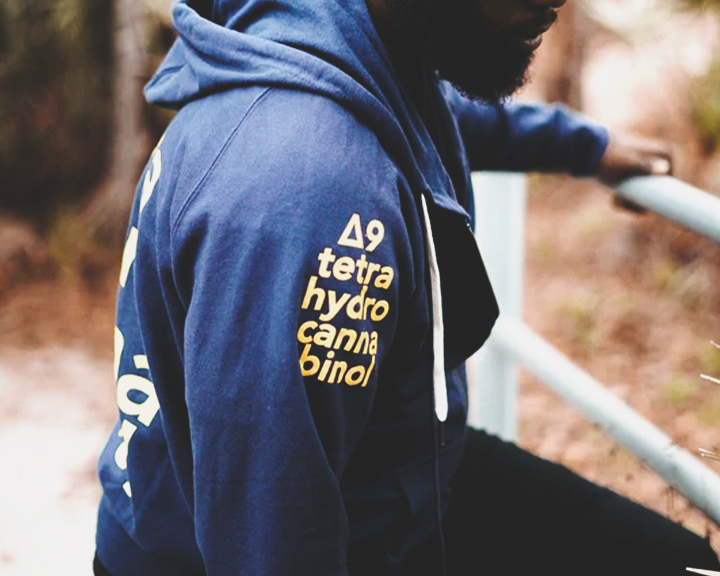 THC Hoodie Een blauwe hoodie met de chemische formule voor THC op de mouw gedrukt.