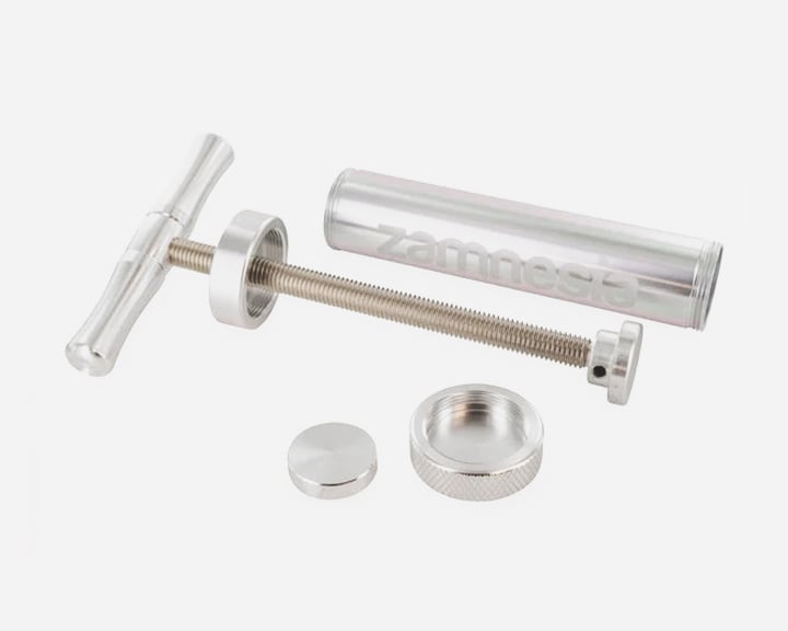 Zamnesia Super Pollen Press Een zilveren metalen spuit met een handvat en een zuiger.